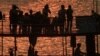 Tourists are silhouetted as they watch sunset from the roof of a wooden boat on the Tonle Sap River near Chroy Changvar village in Phnom Penh, Cambodia, Friday, Jan. 18, 2013.