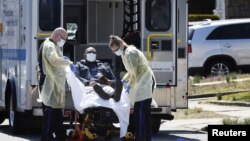 Emergency Medical Technicians lift a patient that was identified to have coronavirus disease into an ambulance while wearing protective gear, in New York City, New York, March 26, 2020.