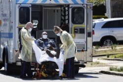 Emergency Medical Technicians lift a patient that was identified to have coronavirus disease into an ambulance while wearing protective gear, in New York City, New York, March 26, 2020.