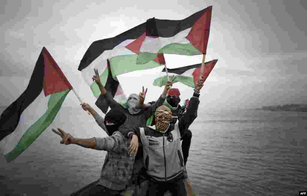 Para pemuda Palestina melambai-lambaikan bendera nasional mereka menjelang peluncuran inisiatif konvoi perahu-perahu kecil yang mereka namakan &quot;Koalisi Pemuda Intifada&quot; untuk mematahkan blokade laut militer Israel atas kota Gaza.