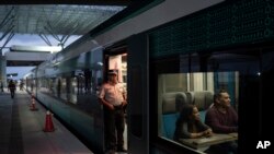 ARCHIVO - Un trabajador del tren maya espera que los pasajeros aborden el vagón en Cancún, México, el miércoles 6 de marzo de 2024. Cuando el proyecto sea completado, el tren de alta velocidad recorrerá varios puntos de la península de Yucatán en el sureste de México.