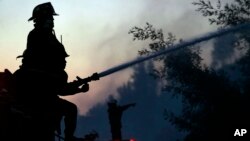 A firefighter sprays water into a burning forest in Valparaiso, Chile, March 14, 2015. 