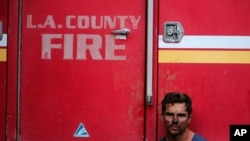 Los Angeles County Firefighter Collin Bashara takes rest with his fire truck in Los Angeles, Monday, Oct. 28, 2019.