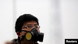 Seorang pria mengenakan masker di tengah-tengah asap kabut di Beijing 22 Februari 2014. 