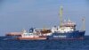 A coast guard boat approaches the German humanitarian group's rescue boat Sea Watch 3, to deliver food and blankets for the cold, off the coast of Syracuse, Italy, Jan. 27, 2019. 