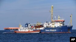 A coast guard boat approaches the German humanitarian group's rescue boat Sea Watch 3, to deliver food and blankets for the cold, off the coast of Syracuse, Italy, Jan. 27, 2019. 