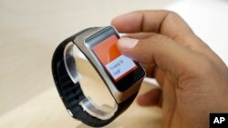 In this June 25, 2014, file photo, a man looks at the Samsung Gear Live, an Android Wear smartwatch, on the demo floor at Google I/O 2014 in San Francisco. 