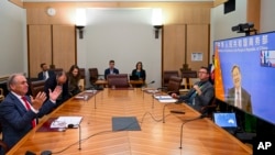 FILE - Australian Trade Minister Don Farrell, left, gestures as he speaks to China's Minister of Commerce, Wang Wentao during a meeting via teleconference at Parliament House in Canberra, Australia, Feb. 6, 2023.