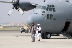 FILE - Taliban members walk in front of a military airplane a day after the U.S. troops' withdrawal from Hamid Karzai International Airport in Kabul, Afghanistan, Aug. 31, 2021.