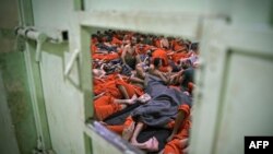 FILE - Men suspected of being affiliated with the Islamic State group gather in a prison cell in the northeastern Syrian city of Hasakeh, Oct. 26, 2019.