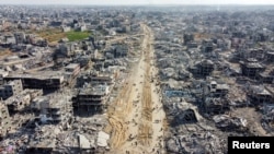 Pemandangan dari drone menunjukkan warga Palestina berjalan melewati puing-puing rumah dan bangunan, menyusul gencatan senjata antara Israel dan Hamas, di Jabalia di Jalur Gaza utara, 19 Januari 2025. (Foto: REUTERS/Mahmoud Al-Basos)