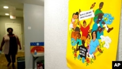 A sign adorns a wall as Pamela Young walks the hallway at United Fort Worth, a grassroots community organization in Fort Worth, Texas, Aug. 10, 2021. New Census Bureau data show the nation's changing racial numbers.