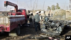 Afghan police inspect the wreckage of a car in which a district chief, his son and a bodyguard were killed by a car bomb in Kandahar, 15 June 2010