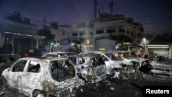 Polisi memeriksa mobil-mobil yang hangus terbakar di Asrama Brigade Mobil (Brimob) di Petamburan, Jakarta, 22 Mei 2019. (Foto: Antara Foto/Sigid Kurniawan via Reuters)