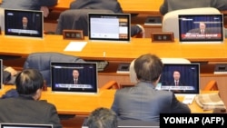 South Korean lawmakers watch screens showing a news broadcast of President Yoon Suk Yeol's speech on lifting martial law, at the main conference hall of the National Assembly in Seoul, early on Dec. 4, 2024.