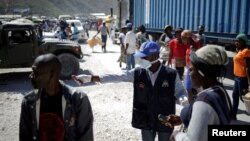 Seorang petugas dari Kementerian Kesehatan Masyarakat dan Populasi meminta seorang perempuan Haiti yang kembali dari Republik Dominika untuk menjalani tes virus corona, di Malpasse, Haiti, 5 Maret 2020. (Foto: Reuters)