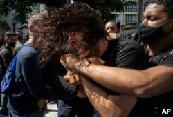 FILE - Plainclothes police detain an anti-government protester during a protest against ongoing food shortages and high prices of foodstuffs, in Havana, Cuba, July 11, 2021.