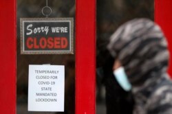 FILE - A pedestrian walks by The Framing Gallery, closed due to the COVID-19 pandemic, in Grosse Pointe, Michigan, May 7, 2020.