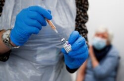 FILE - A health worker fills a syringe with a dose of the AstraZeneca COVID-19 vaccine at a pharmacy in Widnes, Britain, Jan. 14, 2021.
