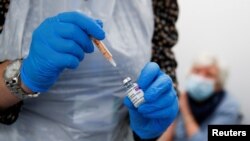 FILE - A health worker fills a syringe with a dose of the AstraZeneca COVID-19 vaccine at a pharmacy in Widnes, Britain, Jan. 14, 2021.