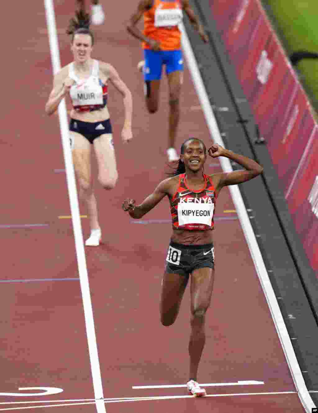Faith Kipyegon, of Kenya celebrates after winning gold ahead of Laura Muir, of Britain, silver, after the final of the women's 1,500-meters at the 2020 Summer Olympics, Friday, Aug. 6, 2021, in Tokyo, Japan. (AP Photo/Francisco Seco)