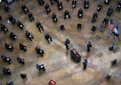 Mourners pay their respects during a ceremony memorializing U.S. Capitol Police officer Brian Sicknick, as an urn with his cremated remains lies in honor on a black-draped table at the center of the Capitol Rotunda, Feb. 3, 2021.