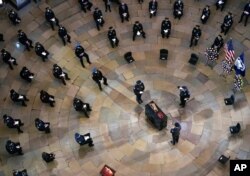 Mourners pay their respects during a ceremony memorializing U.S. Capitol Police officer Brian Sicknick, as an urn with his cremated remains lies in honor on a black-draped table at the center of the Capitol Rotunda, Feb. 3, 2021.