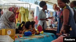 The Senegalese toymaker Awa Gaye presents her dolls to a girl at her stand, in Dakar, Senegal December 14, 2024.