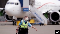 FILE - A security guard at a Boeing airplane manufacturing plant looks out in view of a Boeing 737 MAX jet April 29, 2020, in Renton, Wash. 