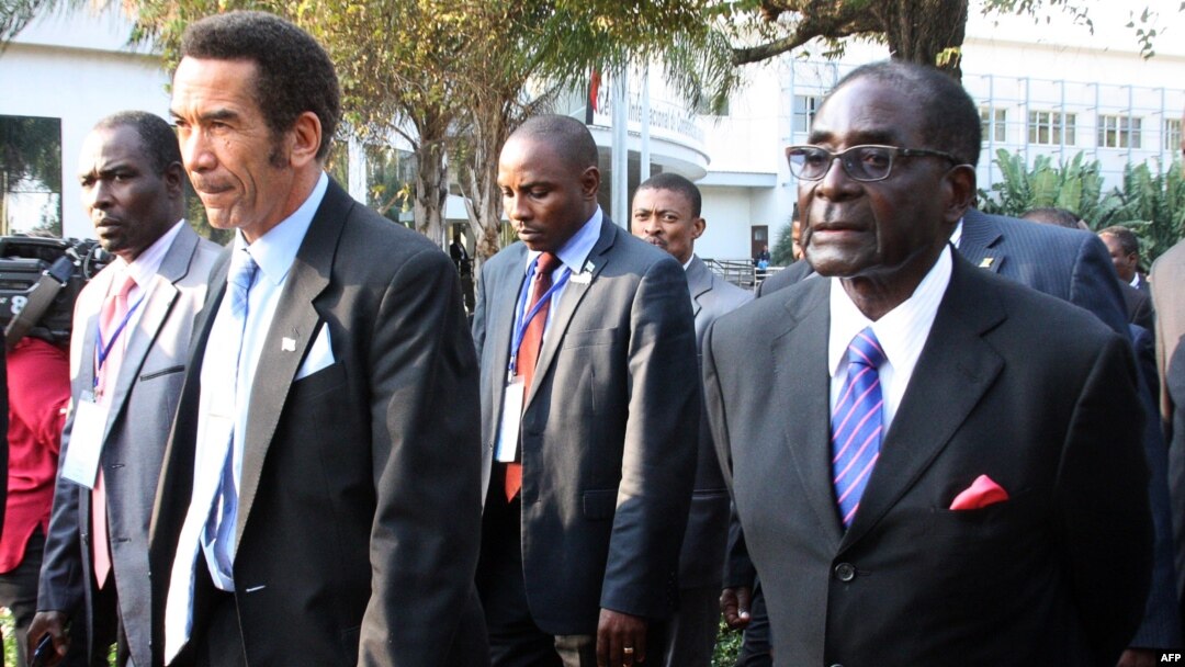 Botswana President Ian Khama (L) walks alongside Zimbabwe President Robert Mugabe (R) during a lunch break at the SADC summit in Maputo, June 15, 2013. 