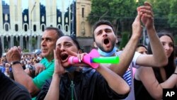FILE - People react while listening to a speaker during a protest as opposition demonstrators gather in front of the Georgian parliament building, in Tbilisi, Georgia, June 24, 2019.