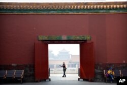 A visitor wearing a face mask to protect against the new coronavirus walks through the Forbidden City in Beijing, May 1, 2020.
