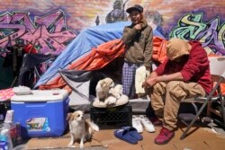 Lucio Lopez, kiri, berbicara dengan teman-temannya saat dia berdiri di tenda yang merupakan bagian dari perkemahan tunawisma di wilayah Queens, New York, Selasa, 13 April 2021. (Foto: AP)