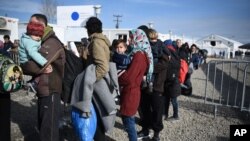 Para migran menunggu diperiksa dokumennya oleh polisi Yunani sebelum diizinkan untuk melalui perbatasan Makedonia, Minggu (21/2). 