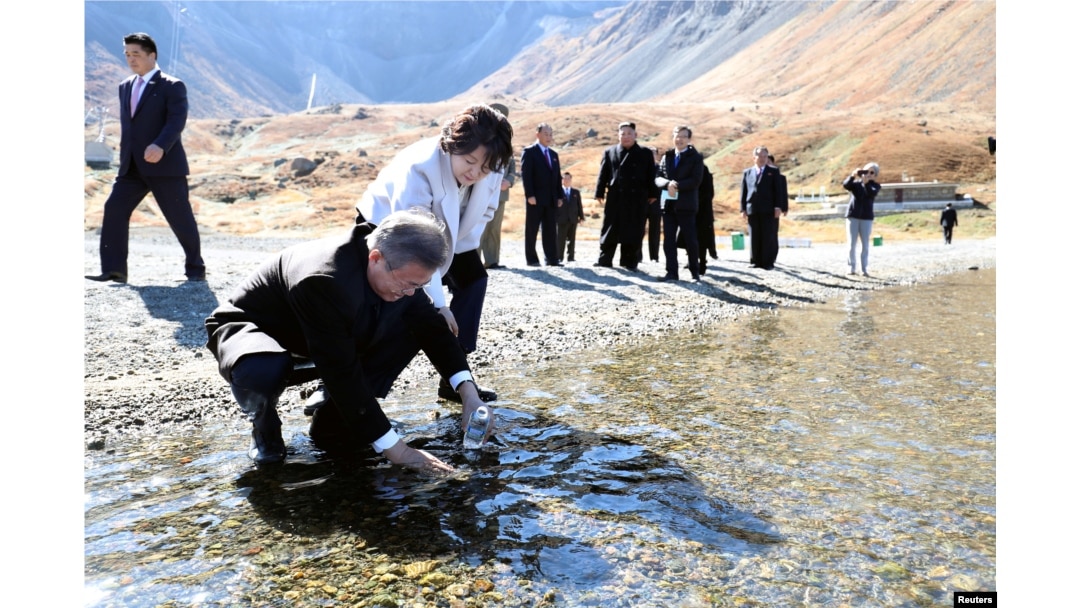 South Korean President Moon Jae-in with his wife, first lady Kim Jung-sook, standing next to him, fills a plastic bottle with water from the Heaven Lake of Mt. Paektu, North Korea, Sept. 20, 2018.