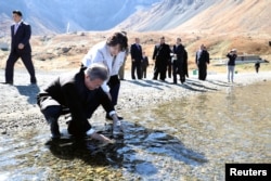 South Korean President Moon Jae-in with his wife, first lady Kim Jung-sook, standing next to him, fills a plastic bottle with water from the Heaven Lake of Mt. Paektu, North Korea, Sept. 20, 2018.
