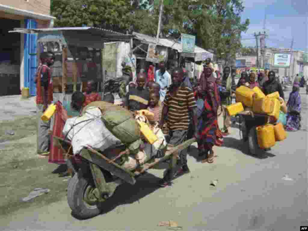 Somalis from southern Somalia carrying their belongings make their way to a new camp for internally displaced people in Mogadishu Somalia, Thursday July, 28, 2011. Heavy fighting erupted Thursday in Somalia's capital as African Union peacekeepers launched