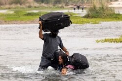 FILE - Asylum-seeking migrants cross the Rio Grande river into the United States from Mexico, in Del Rio, Texas, May 10, 2021.