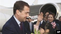A Chinese girl greets Russia President Dmitry Medvedev, left, upon his arrival at the Beijing Capital International Airport Sunday, Sept. 26, 2010.