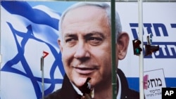 A woman walks by an election campaign billboard showing Israeli Prime Minister Benjamin Netanyahu in Tel Aviv, March 28, 2019. 
