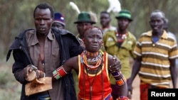 A man holds onto a girl as he brings her back to her family home after she tried to escape when she realized she is to be married, about 80 km (50 miles) from the town of Marigat in Baringo County, Kenya.