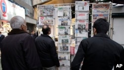 Iranians look at newspapers hanging on a news stand in central Tehran, Feb. 25, 2012.