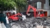 Workers direct a mechanical shovel grabbing pieces of destroyed surfacing to gather up the lead particles in the school yard of Saint Benoit primary school in Paris, France, Aug. 8, 2019.