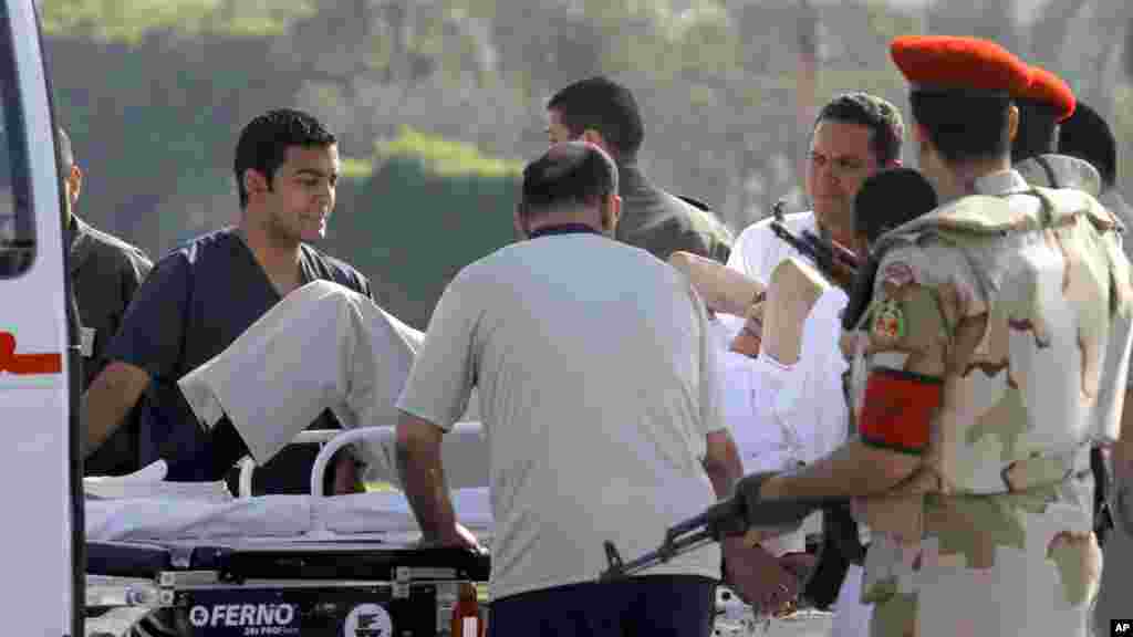 Egyptian medics and police escort former Egyptian President Hosni Mubarak into an ambulance after after he was flown by a helicopter to the Maadi Military Hospital from Torah prison, Cairo, August 22, 2013.
