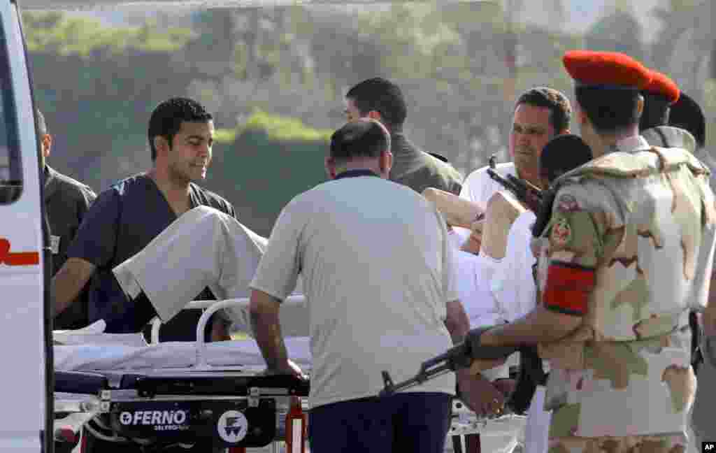 Nhân viên y tế Ai Cập và cảnh sát hộ tống cựu tổng thống Hosni Mubarak vào xe cứu thương sau khi ông được máy bay trực thăng đưa từ nhà tù Torah ở Cairo đến quân y viện Maadi. Nhà lãnh đạo bị lật đổ vừa được phóng thích khỏi tù để nhập viện.