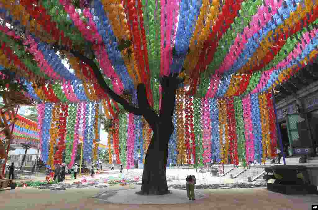 A woman prays as workers prepare to remove lantern decorations after a period of celebrations of Buddha's birthday at the Chogye Temple in Seoul, South Korea.