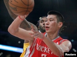 Houston Rockets point guard Jeremy Lin comes under the basket against Los Angeles Lakers center Jordan Hill (27) during their NBA basketball game in Los Angeles, California, Nov. 18, 2012.