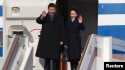 Chinese President Xi Jinping (L) and First Lady Peng Liyuan wave as they disembark from a plane upon their arrival at Moscow's Vnukovo airport, March 22, 2013.