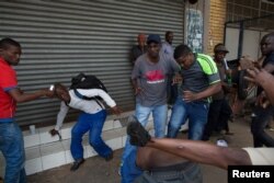 FILE - Somali immigrants hold rocks during clashes in Pretoria, South Africa, Feb. 18, 2017.