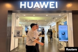 Orang-orang berjalan melewati toko Huawei yang memasang iklan smartphone seri Mate 60, di sebuah pusat perbelanjaan di Beijing, China, 30 Agustus 2023. (Foto: REUTERS/Yelin Mo)
